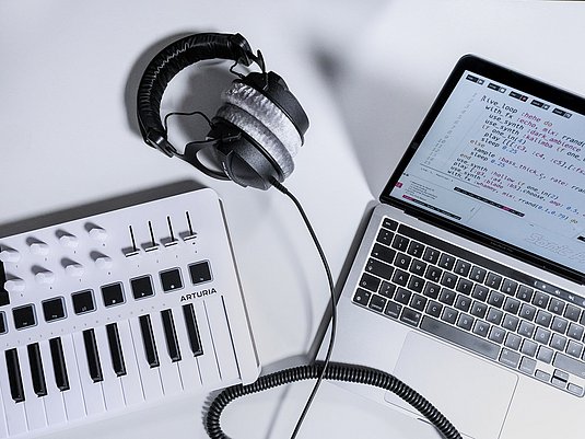 ein MIDI-Keyboard, Kopfhörer und Laptop